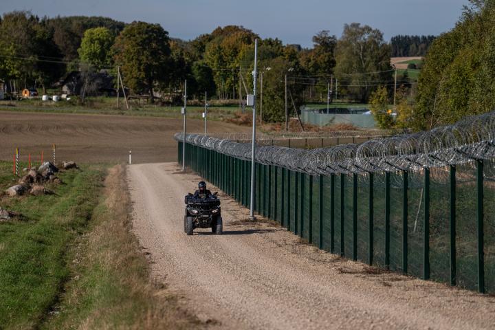 Un agente de la policía fronteriza estonia conduce un quad junto a una valla de alambre de púas que marca la frontera entre Estonia y Rusia.