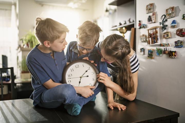 Una familia se prepara para el cambio de hora cambiando las manijas del reloj.
