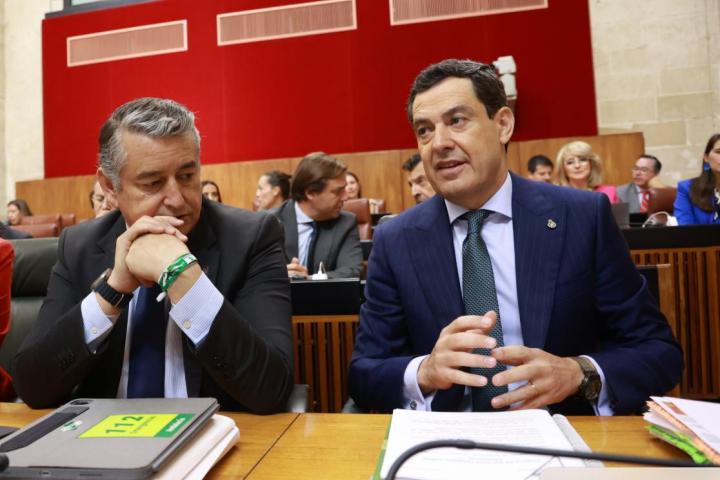 Antonio Sanz y Juanma Moreno conversan en un pleno del Parlamento andaluz, el 11 de junio de 2025.