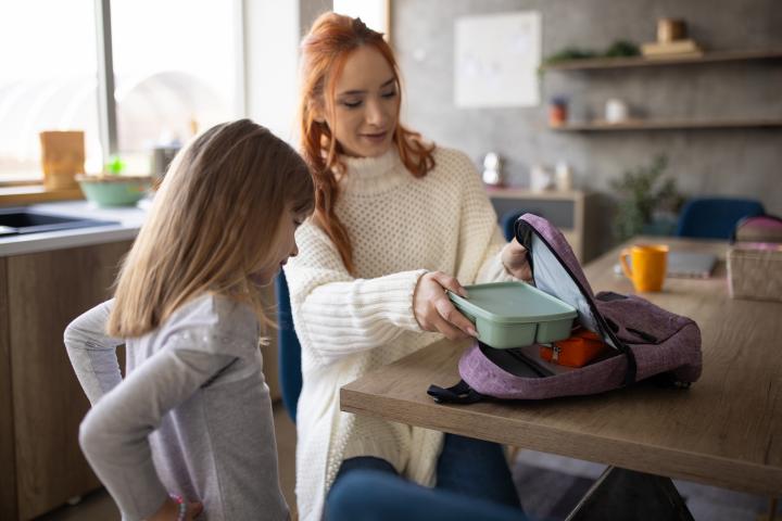 Niña pequeña en casa preparándose para ir al colegio con su madre.