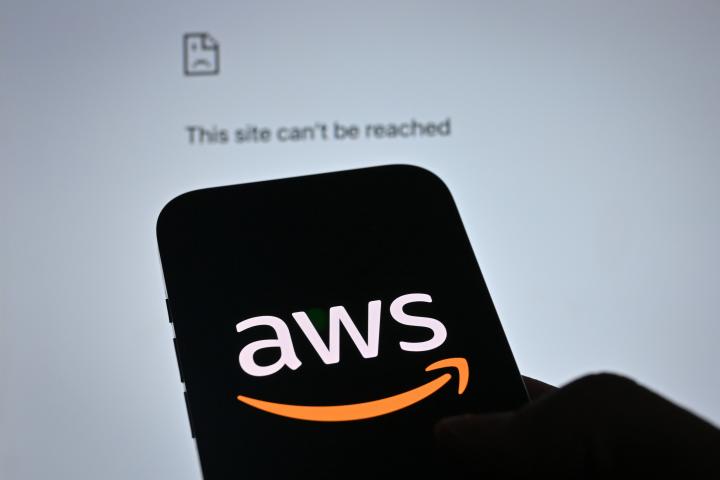 Imagen del logo AWS, con un ordenador caído de fondo.