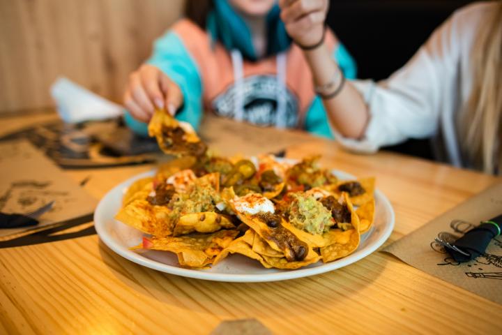 Jóvenes comiendo nachos dentro de un restaurante.