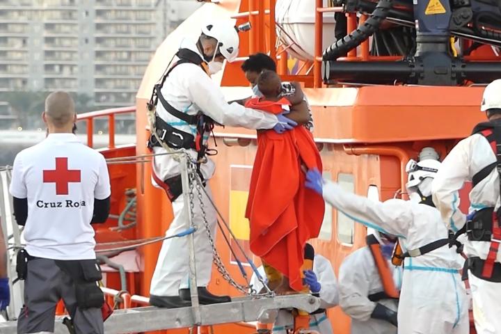 Un miembro de la Cruz Roja ayuda a un niño migrante a bajar del barco, en el puerto de Arguineguín, en Gran Canaria, España.