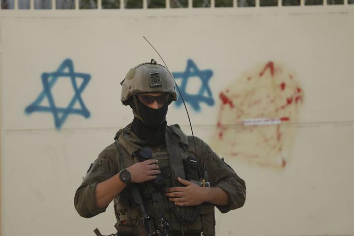 Un soldado de Israel, ante unas pintadas con estrellas de David, en el centro ocupado de Hebrón, en Cisjordania.