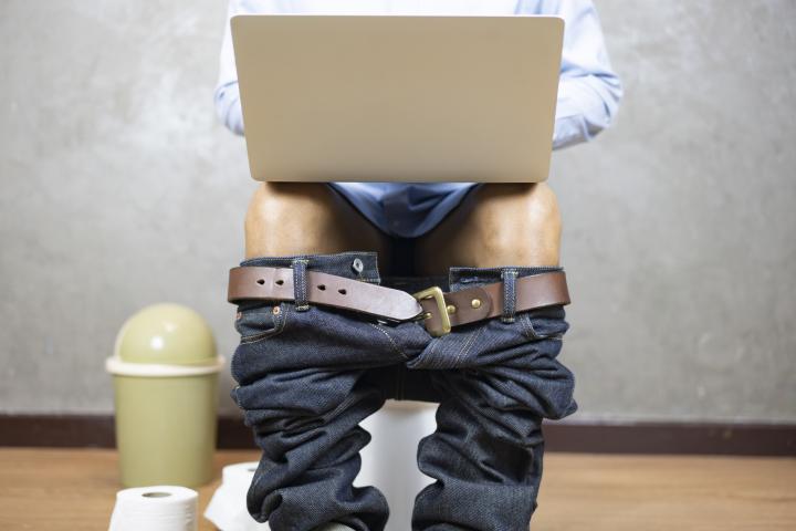 Un señor trabajando desde el baño con su ordenador