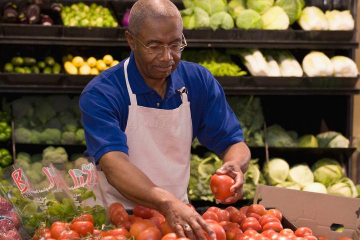 Hombre reponiendo verduras en el supermercado