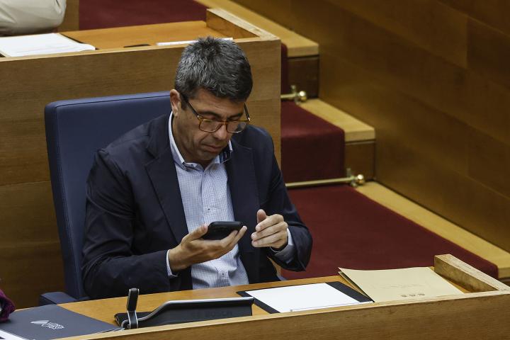 El presidente de la Generalitat Valenciana, Carlos Mazón, habla por teléfono móvil durante una sesión plenaria en Les Corts Valencianes.