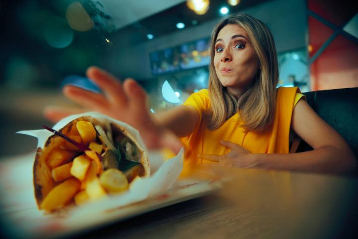Mujer hambrienta alcanzando un plato de shawarma en un restaurante de comida rápida