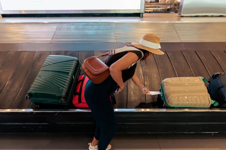 Mujer recogiendo su maleta en la cinta transportadora de equipaje del aeropuerto.