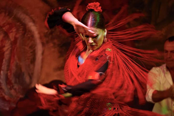 Bailaora de flamenco con vestido rojo actuando en un tablao de Sevilla, uno de los destinos favoritos de los visitantes finlandeses.
