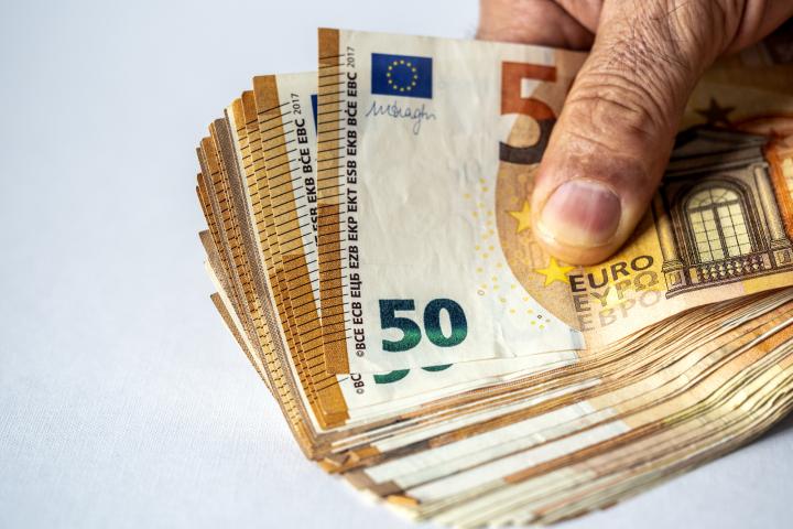 Una mano de un hombre sujetando billetes de 50 euros.