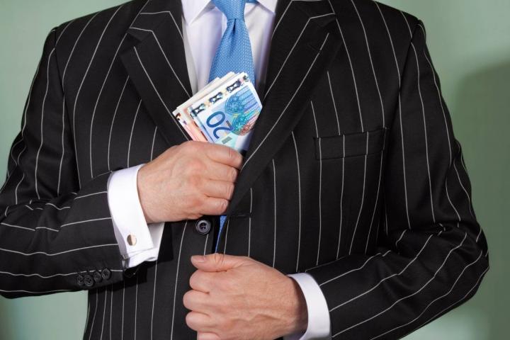 Hombre trajeado esconde su fajo de billetes