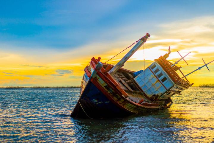 Barco naufragando con atardecer de fondo