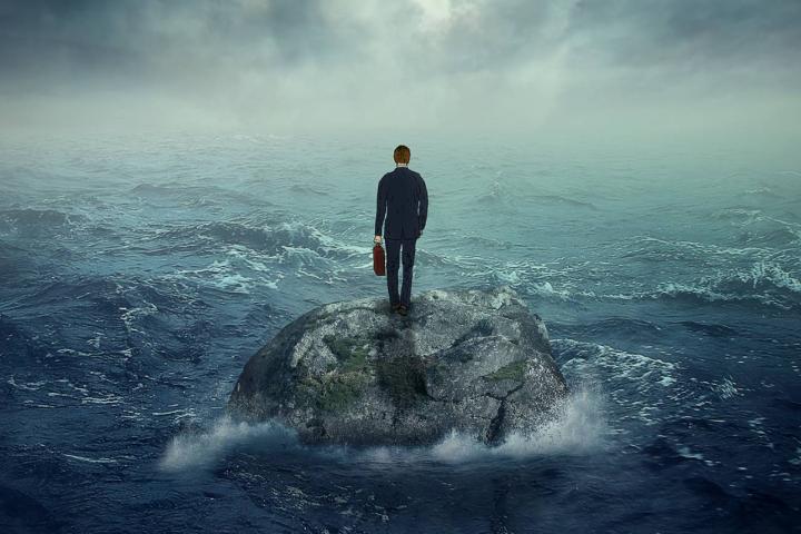 Joven solitario sobre un acantilado rocoso en una isla, rodeado por las olas de una tormenta oceánica