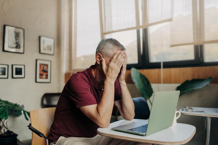 Hombre cansado y molesto delante de su ordenador portátil.