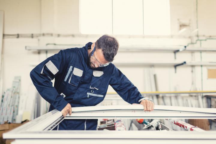 Carpintero de aluminio trabajando en el taller con una estructura metálica.