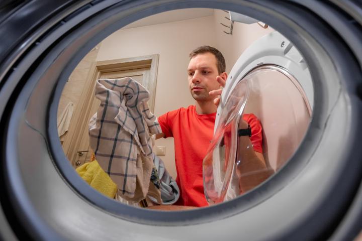 Retrato de un hombre serio lavando ropa sucia en una lavandería.