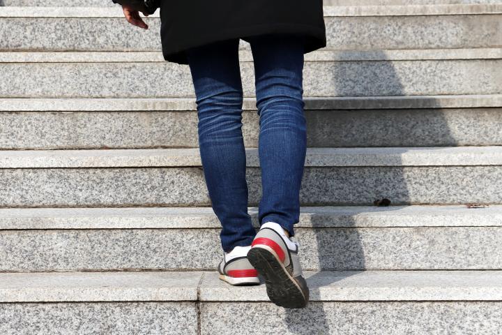 La espalda de una mujer subiendo las escaleras.