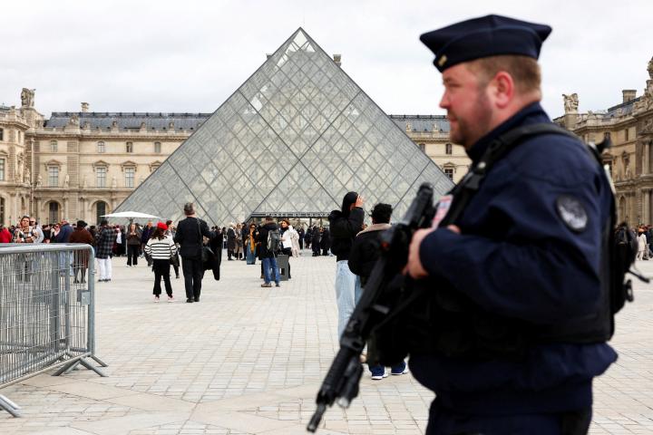 Un agente de la policía antidisturbios francesa patrulla cerca de la pirámide de cristal del Museo del Louvre, tras el robo de joyas, el 27 de octubre de 2025.