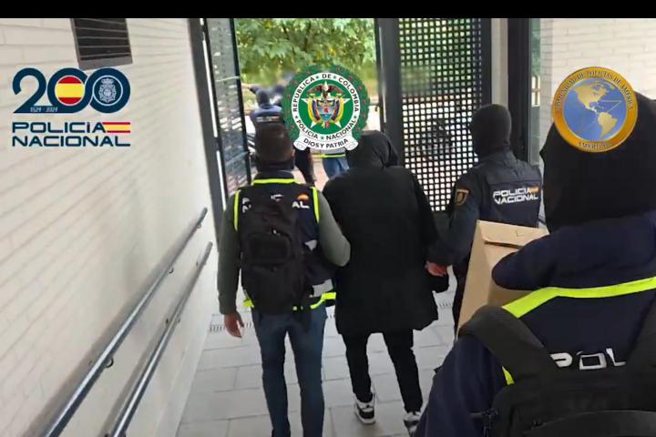 Agentes de la Policía Nacional conducen a uno de los narcotraficantes del Tren de Aragua detenidos hacia un coche patrulla, en el operativo conocido el 7 de noviembre de 2025.