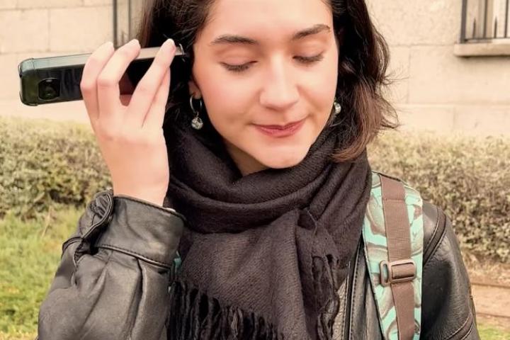 Una joven escucha un fragmento del disco de rosalía con un teléfono móvil