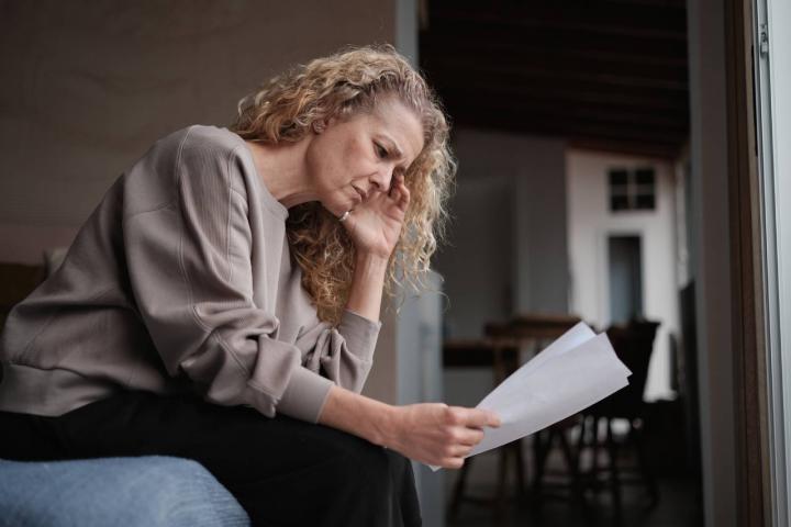 Mujer preocupada leyendo un aviso de multa