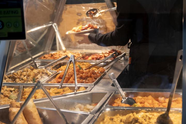 Una persona eligiendo su comida de un buffet libre