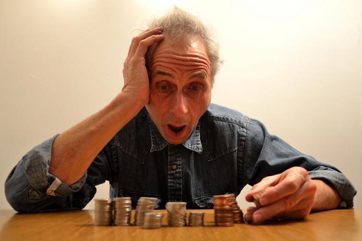 Se ve a un hombre contando fajos de billetes. Pone una cara cómica de sorpresa al ver cuánto/poco tiene.