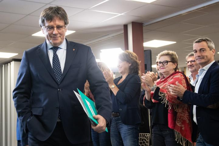 Carles Puigdemont sonriente, aparecer con una carpeta bajo el brazo durante un acto