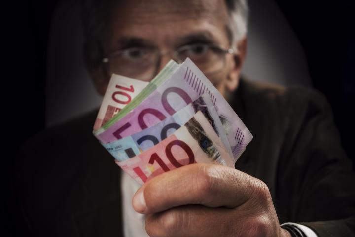 Un hombre enseñando un gran fajo de billetes.