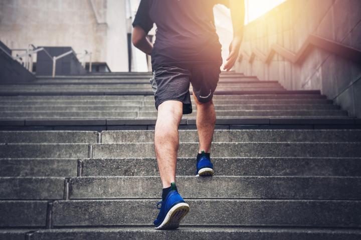 Primer plano de un joven subiendo corriendo las escaleras con ropa deportiva.