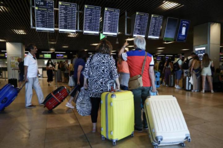 Varias personas mirando el panel informativo de vuelos en un aeropuerto