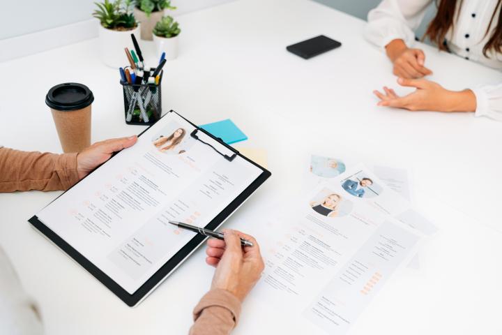Vista superior de mujeres en una entrevista de trabajo, con el foco puesto en un currículum profesional.