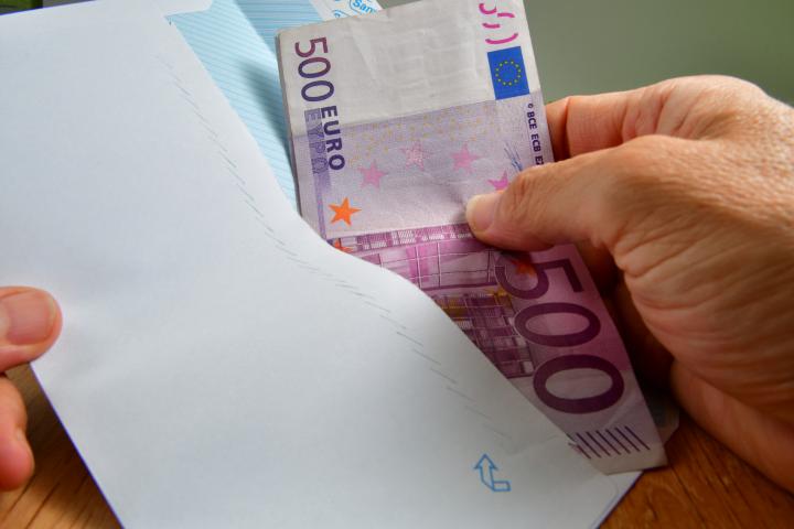 Una persona sacando billetes de 500 euros de un sobre, en una imagen de archivo