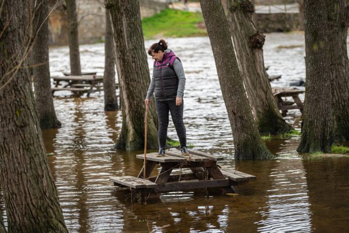 Mujer subida a un banco de madera en una zona inundada por las lluvias intensas.
