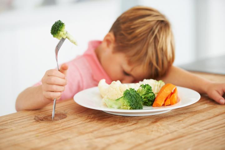 Imagen de archivo de un niño con un plato de verdura.