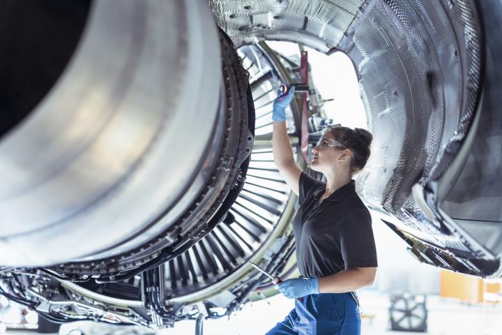 Una mecánica trabajando en el motor de un avión, en una imagen de archivo