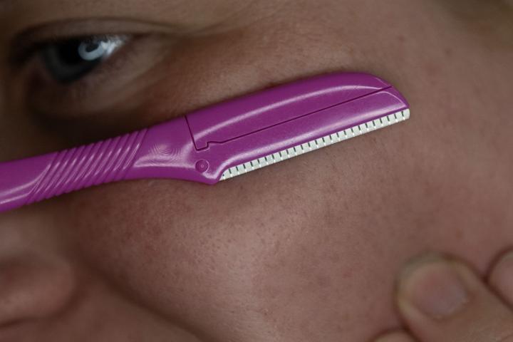 Una mujer utilizando una cuchilla para dermaplaning