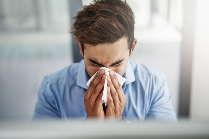 Una persona, sonándose en una oficina.