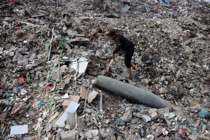 Un niño palestino recoge plástico cerca de un misil sin explotar en un vertedero en la zona del mercado de Firas, en la ciudad de Gaza, el 13 de noviembre de 2025. (Foto de Majdi Fathi/NurPhoto)