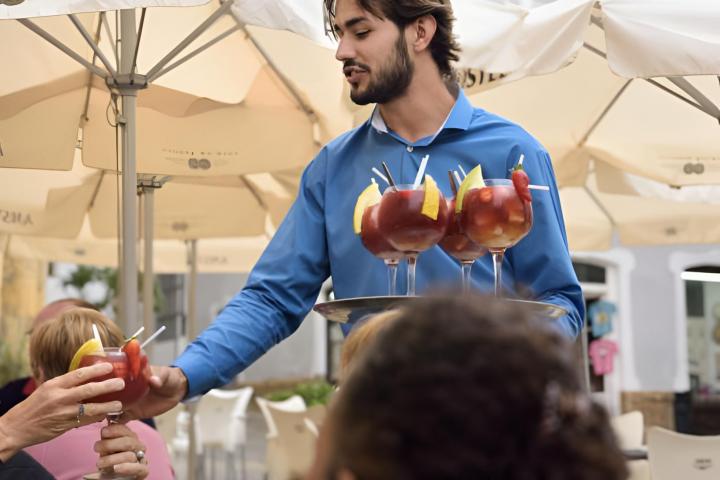Un camarero sirviendo sangría a una mesa llena de turistas
