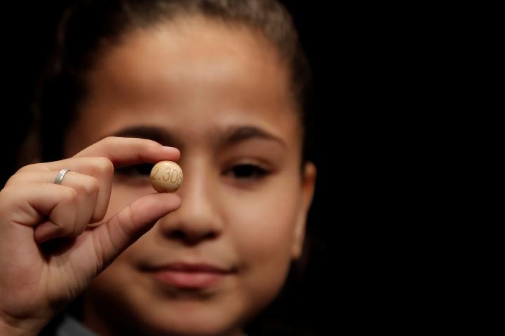 Una niña con una de las bolas del sorteo de Lotería de Navidad.