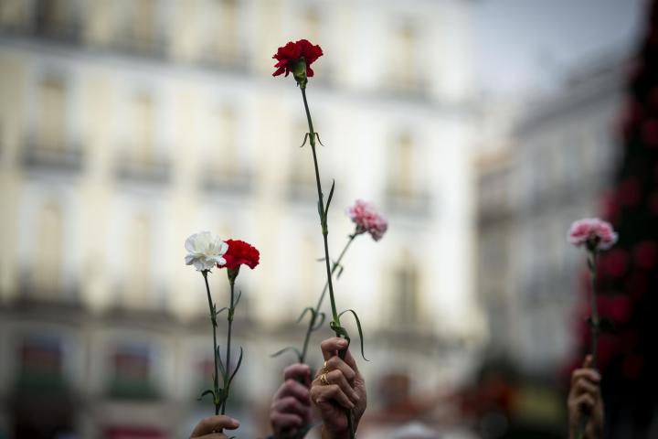 Varias personas sujetan flores durante una manifestación de Marea de Residencias