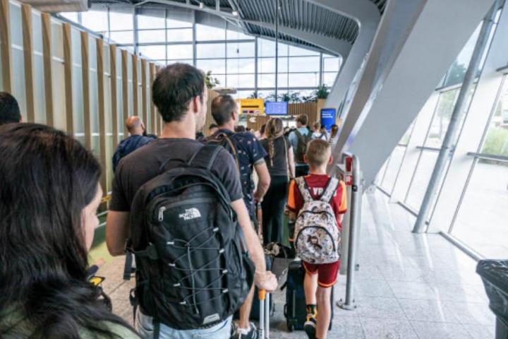 Una fila de personas esperando para pasar el control de seguridad del aeropuerto