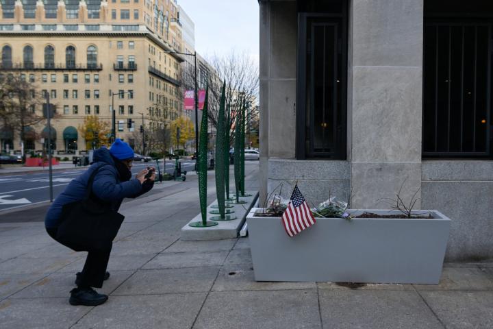 Un hombre fotografía las flores y la bandera colocadas en homenaje a los agentes tiroteados en Washington.