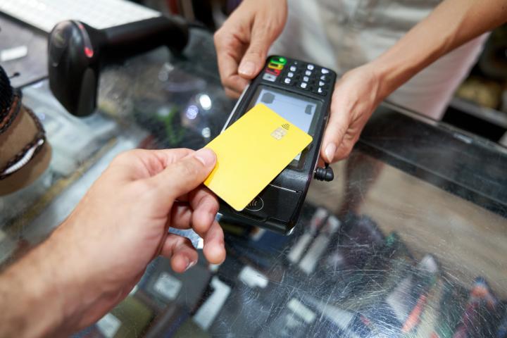Una persona realizando una compra en una tienda dependiente a través de su tarjeta bancaria.