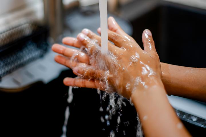 Persona lavándose las manos con jabón y agua.