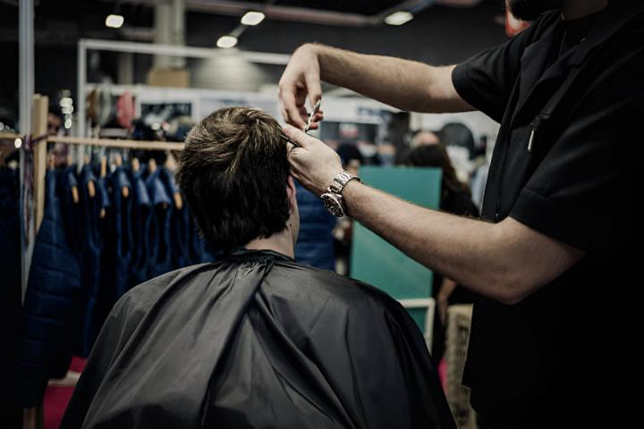 Un barbero cortando el pelo a un cliente en una foto de archivo