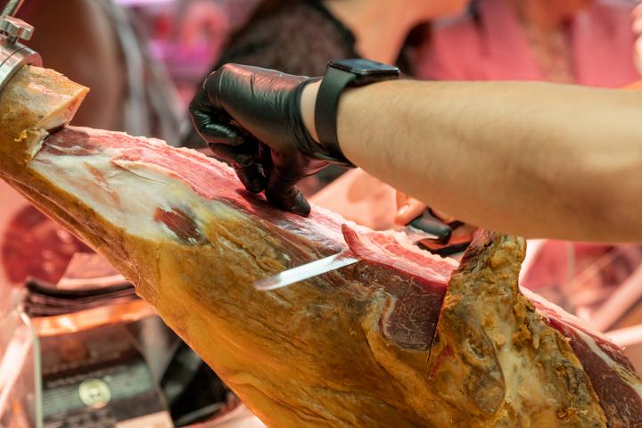 Cortador de jamón trabajando en un centro comercial con guantes