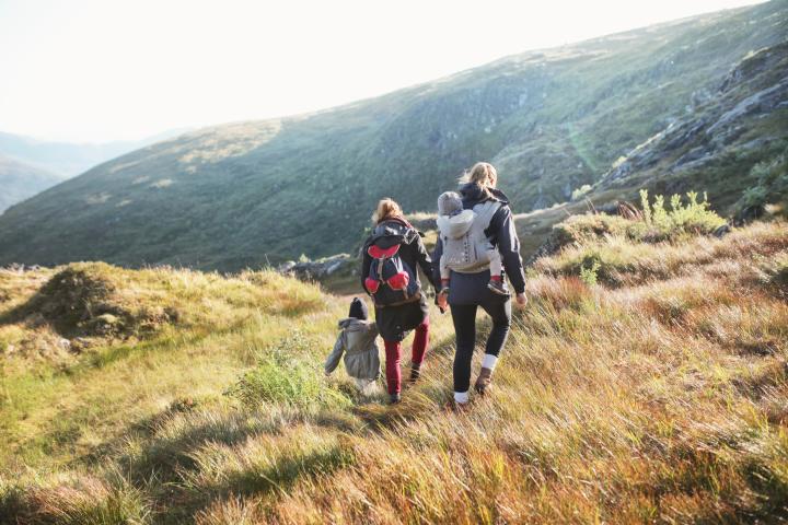 Familia, de espaldas, caminando por las montañas de Noruega.
